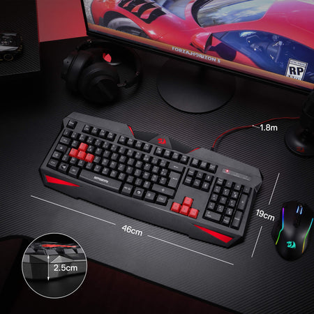 Gaming keyboard with red accents on a desk setup with a monitor, mouse, and headset.