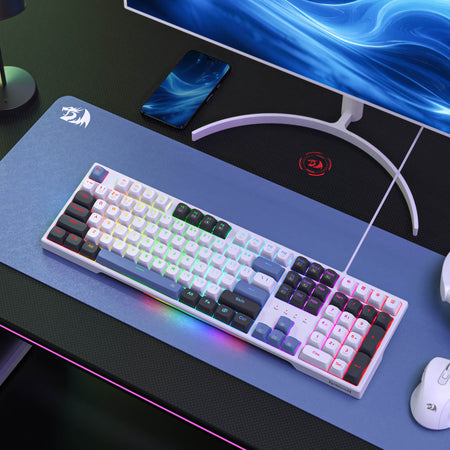 Gaming keyboard on a desk with a monitor, mouse, and phone in the background