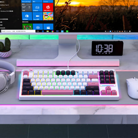 Keyboard on a desk with a computer monitor displaying a colorful interface, clock, and cactus plant.