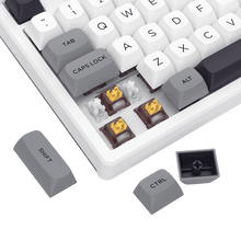 Close-up of a mechanical keyboard with white keycaps and gold accents on a black background.
