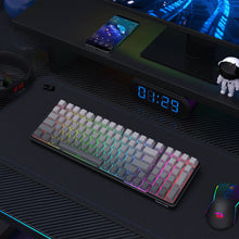 Gaming keyboard with RGB lighting on a desk setup with phone, mouse, and decor.