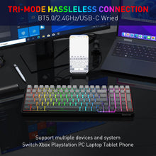 Keyboard with RGB lighting on a desk with multiple devices in the background